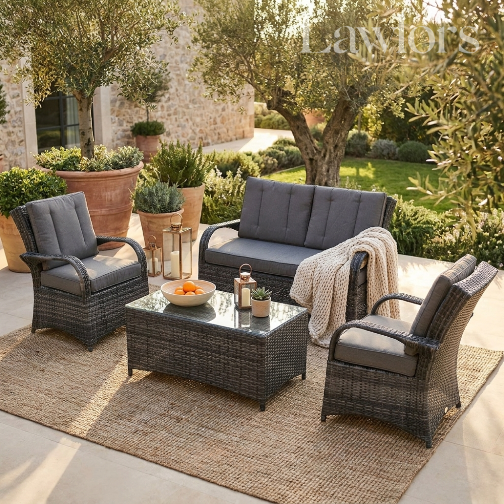 Outdoor garden furniture patio set with gray cushions and a coffee table in a garden setting.