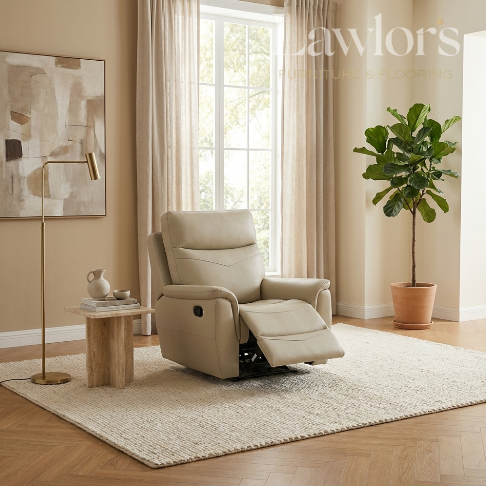 A beige leather recliner chair with its footrest extended, styled in a bright, modern living room with a light-colored rug, wooden floor, a potted plant, and a gold floor lamp.