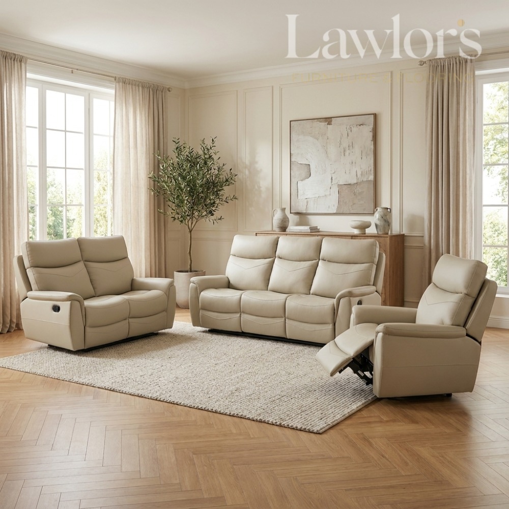 A staged living room showing a coordinated beige leather recliner set: a loveseat, a three-seat sofa, and a matching recliner on a light rug over herringbone wood flooring. Large windows, curtains, a plant, and wall art are visible.