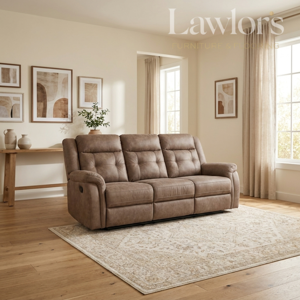 A brown tufted three-seater sofa in a styled living room with beige walls, wood floors, a patterned rug, and framed wall art.