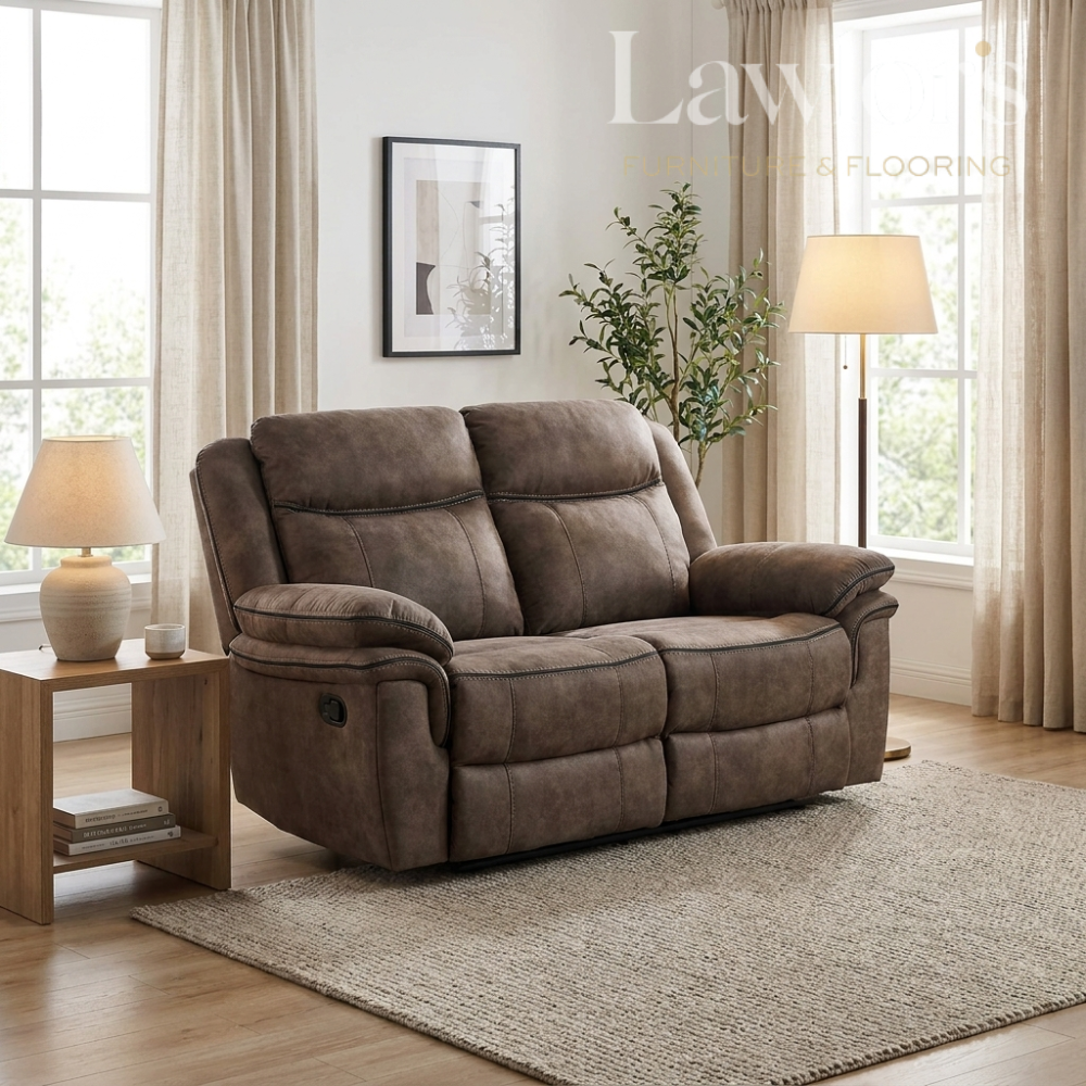 Brown 2 seater recliner sofa in a living room setting with a lamp and plant.