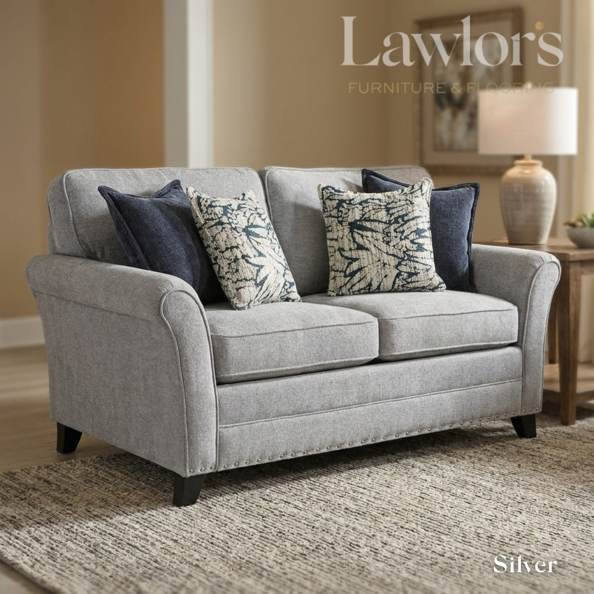 Silver 2 seater fabric sofa with decorative pillows in a living room setting