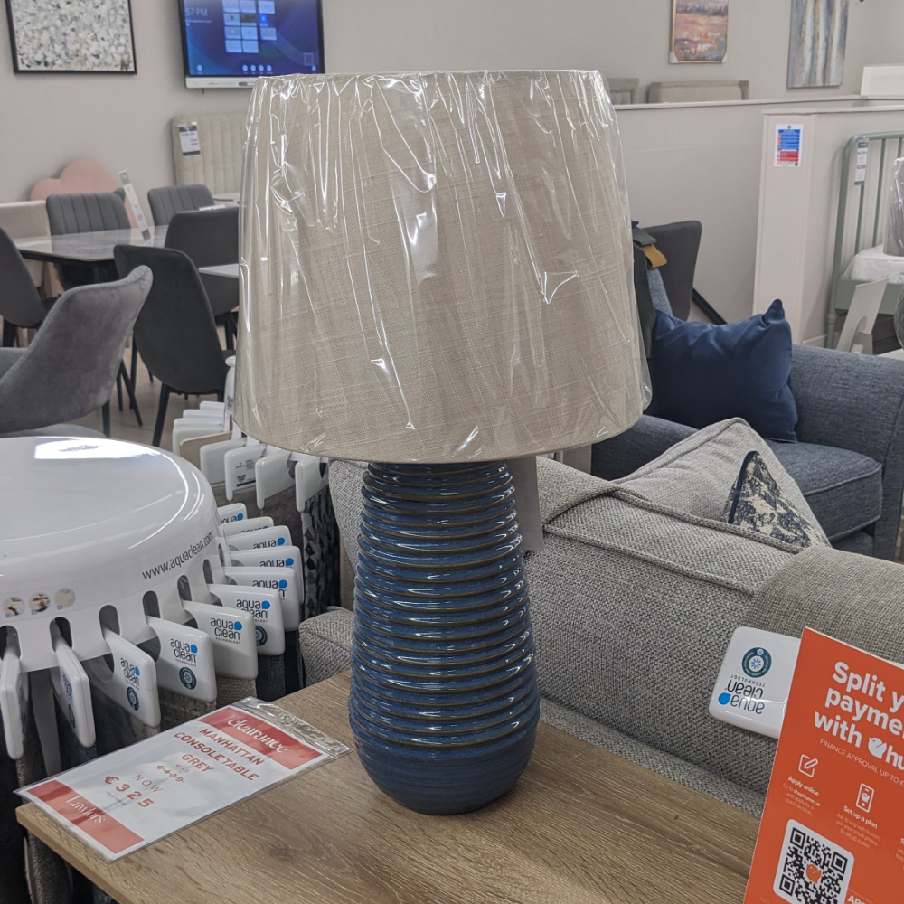 The Ridge Blue Ceramic Table Lamp 58cm features a circular textured base and cream shade with a 58cm tall lamp that adds style and warmth to any room