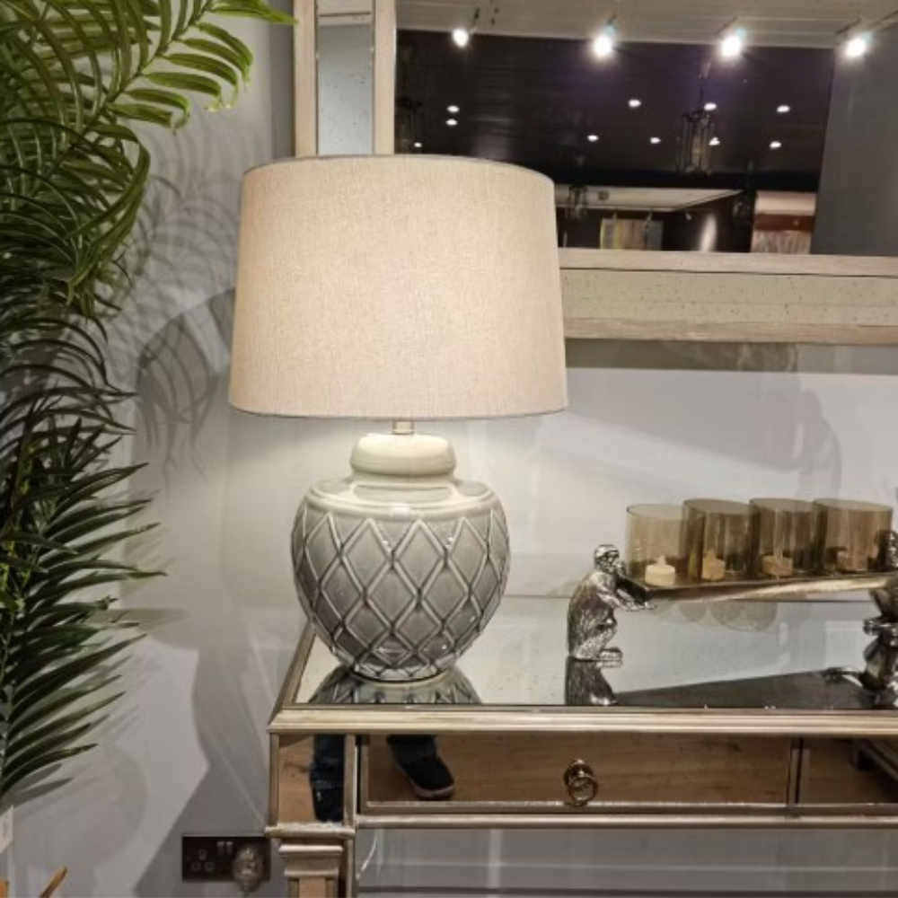 The Rina Ceramic Table Lamp features a green geometric ceramic base and beige fabric shade, a modern design that adds elegance and warmth