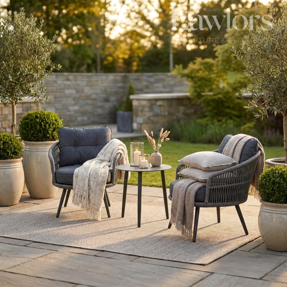 Outdoor garden furniture patio setting with two chairs, a table, and decorative elements on a stone patio.
