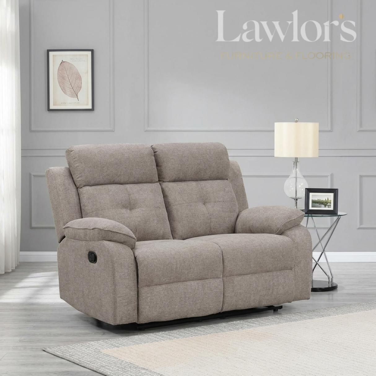 Light brown 2 seater recliner sofa in a living room setting with a lamp and framed picture on a gray wall.