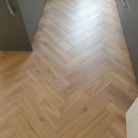 The Alicante Herringbone Laminate Flooring - 12mm features AC6-rated, underfloor heating compatible, classic herringbone design.