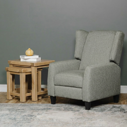 Grey armchair next to a wooden side table against a grey wall.