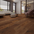 Brown hardwood flooring installed in a modern living room with a beige sectional sofa, pink armchair, and large windows.
