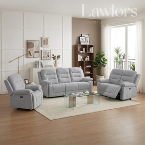 A light gray three-piece reclining living room furniture set including a sofa, two armchairs, and a glass-top coffee table, staged in a modern living room with wood floors, a white rug, and a window.