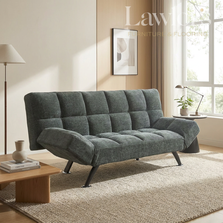 Green sofa bed in a living room setting with a lamp and coffee table.