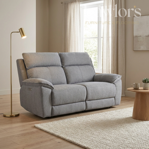 Grey 2 seater electric recliner sofa in a living room with a lamp and small table.