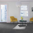 A modern living room scene featuring dark gray stone-look floor tiles, two yellow armchairs, a black round coffee table with a glass vase of flowers, and a white paper lantern pendant light hanging from a white ceiling.