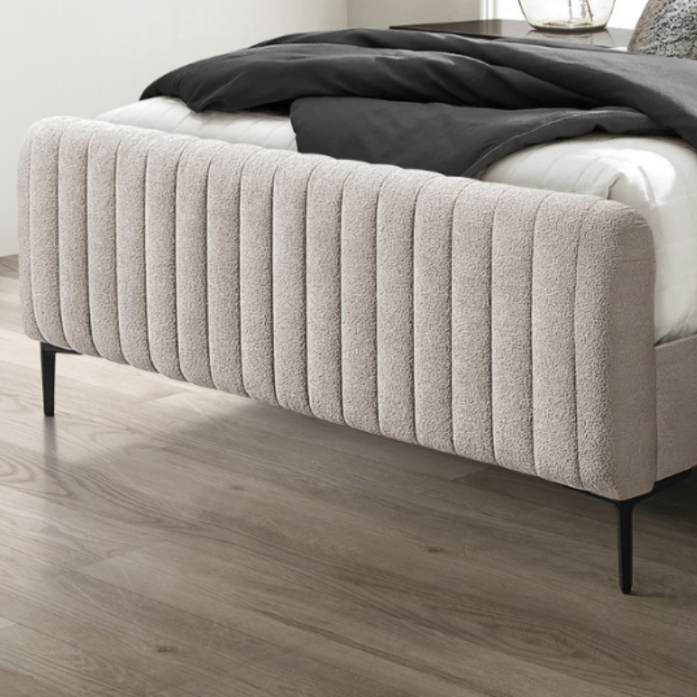 The Clarissa Bed in Grey or Beige features chic channelled upholstery, sturdy metal legs, and padded headboard.