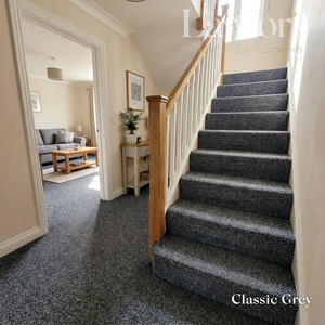 Staircase with gray carpeting leading to a living room