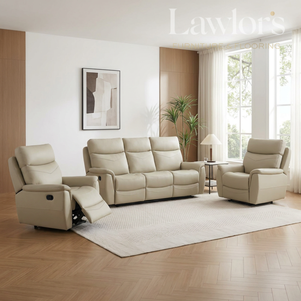 A light beige leather recliner, loveseat, and armchair set arranged in a bright, modern living room with wood flooring, a white rug, and large windows.