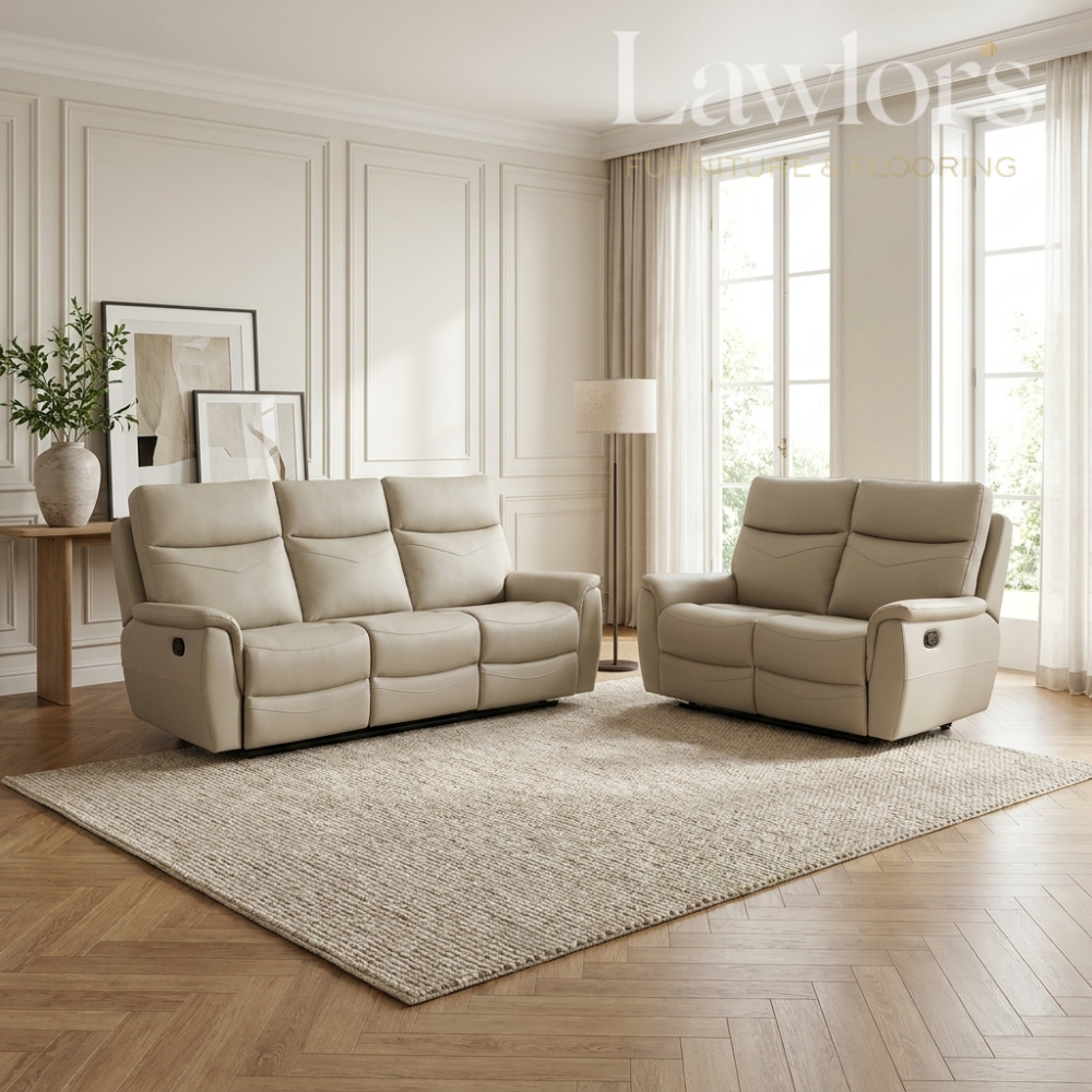 A beige leather reclining loveseat and matching armchair arranged on a large textured area rug in a bright, modern living room with wood floors, paneled walls, and tall windows.