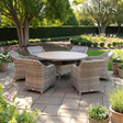 Outdoor garden furniture patio set with wicker chairs and a round table in a garden setting.