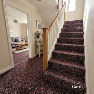 Staircase with garnet carpet leading to a living room.
