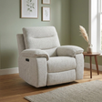 A light beige textured fabric recliner chair shown in a styled living room setting with a wooden floor, sage green wall, framed botanical prints, a small wooden side table with a vase of pampas grass, and a neutral rug.