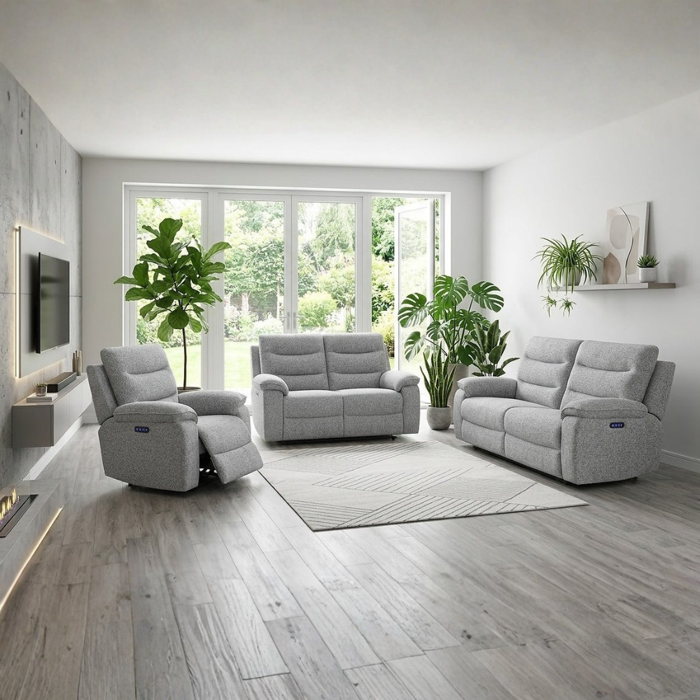 A modern living room setup featuring a light gray recliner, a matching two-seater sofa, and a three-seater sofa in textured light gray fabric, arranged on a neutral rug over gray wood-look flooring. The room is styled with potted green plants and a wall-mounted TV.