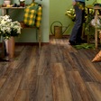 Brown wood-look plank flooring installed in a garden center or nursery setting, with a person visible in the background near plants and tables.