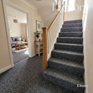 Staircase with dark gray carpet leading to a living room