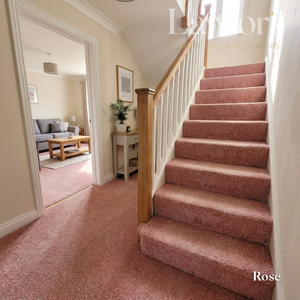 Staircase with rose-colored carpet leading to a living room