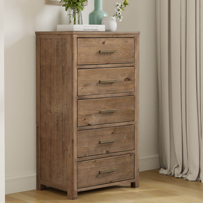 Wooden dresser with five drawers in a bedroom setting.