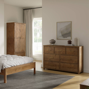 Wooden bedroom furniture including a bed, wardrobe, and dresser in a room with a window and decor.