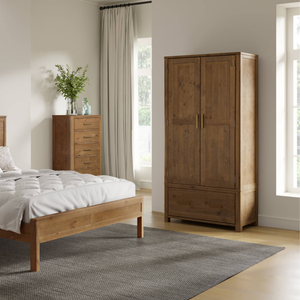 Wooden wardrobe and bed in a bedroom with light-colored walls and curtains.