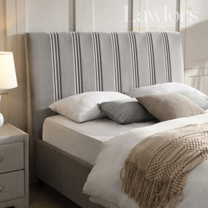 Bedroom with a bed featuring a striped headboard, pillows, and a nightstand with a lamp.