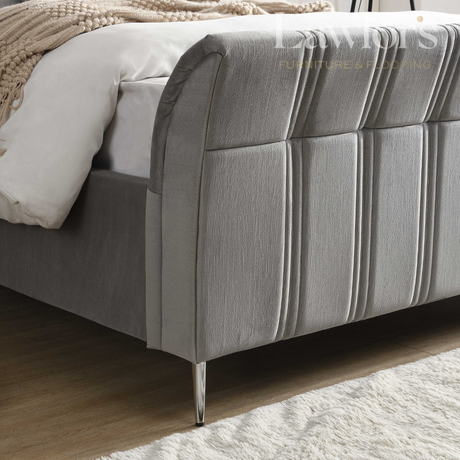 Gray upholstered bed with a textured headboard in a bedroom setting.