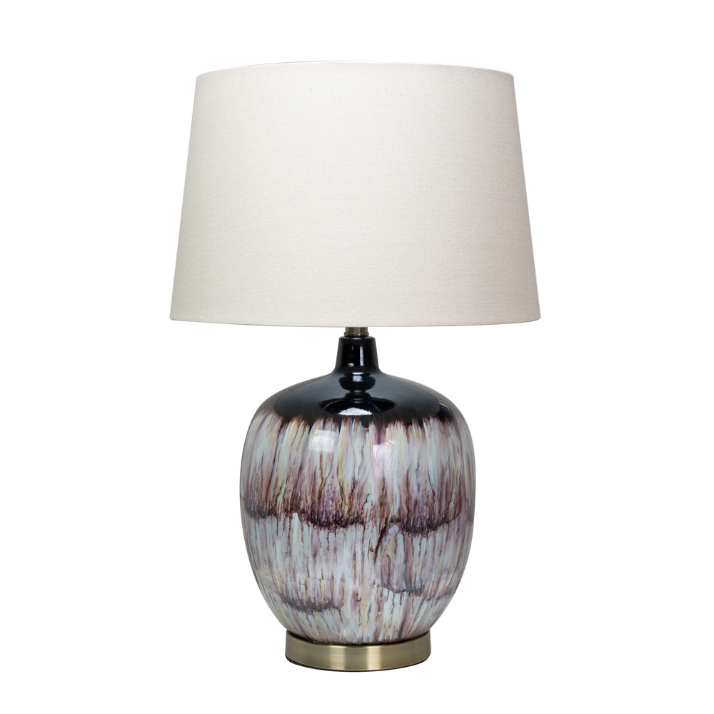 The Lara Table Lamp features a bottle-shape body, a mix of purple, lilac, pink, and damson hues, a ring of antique gold metal and gently flared white shade.