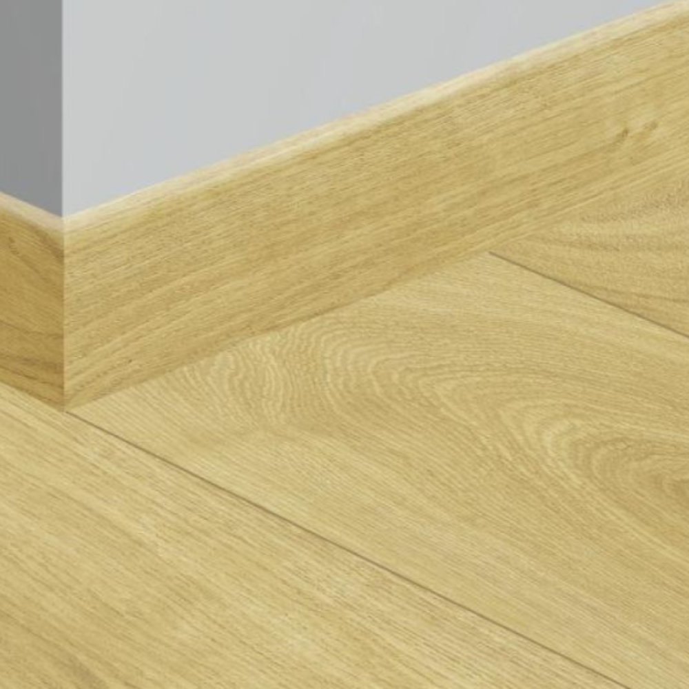 Light oak wood flooring planks with a natural wood grain finish, shown meeting a white baseboard against a light gray wall.