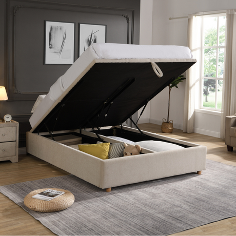 The Lily Gas-Lift Fabric Ottoman features a plush button accent, soft-touch beige fabric, storage convenience and stylish winged sides.