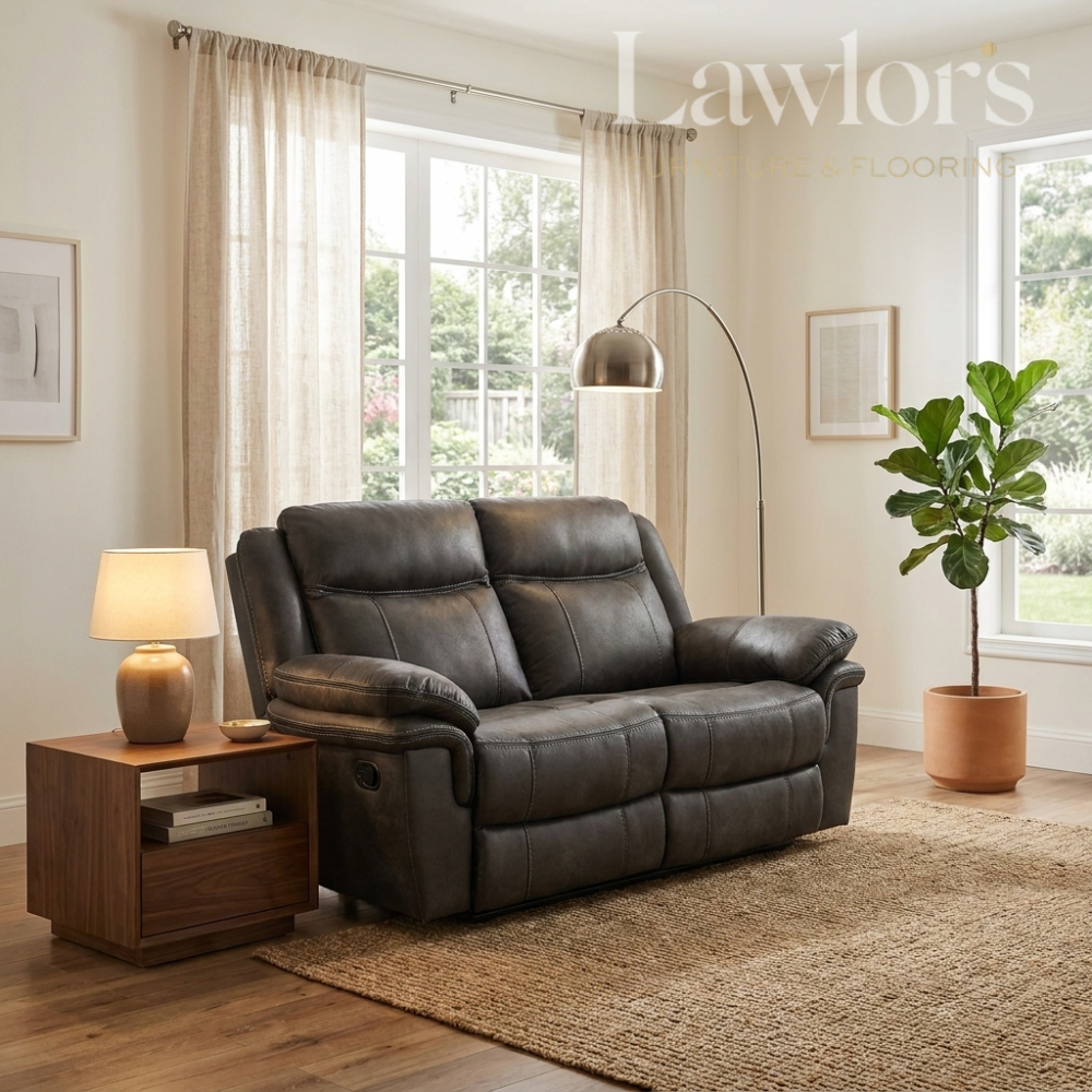 Grey leather 2 seater sofa in a living room with a lamp, side table, and plant.