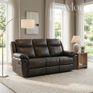 Grey leather 3 seater sofa in a living room setting with a lamp and window.