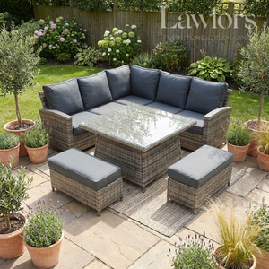Outdoor garden furniture patio set with gray cushions on a stone patio, surrounded by potted plants.