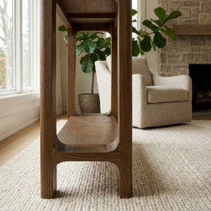Wooden side table in a living room with a beige armchair and plant.