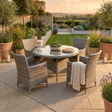 Outdoor garden furniture patio set with table and chairs on a stone patio, surrounded by plants.