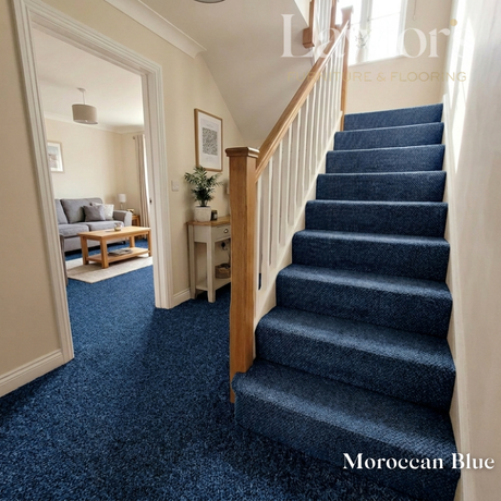 Staircase with blue carpeting leading to a living room