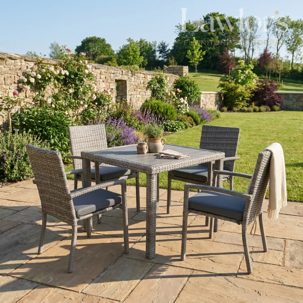 Outdoor garden furniture patio set with table and chairs on a stone patio, surrounded by greenery.