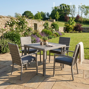 Outdoor garden furniture patio set with table and chairs on a stone patio, surrounded by greenery.
