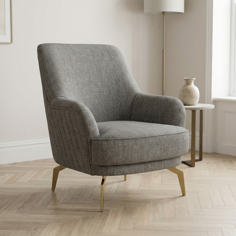 Gray armchair in a room with a lamp and vase on a side table.