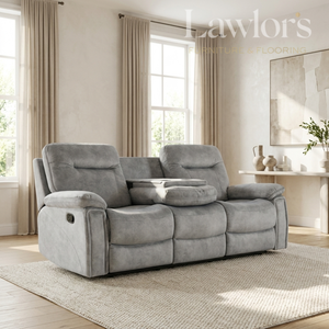 A gray reclining loveseat with two seat backs and a center console table, shown in a styled living room setting with beige curtains, a rug, and a console table.