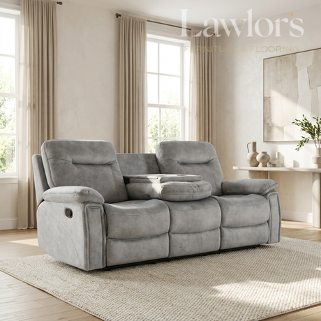 A gray reclining loveseat with two seat backs and a center console table, shown in a styled living room setting with beige curtains, a rug, and a console table.