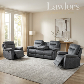 A staged living room showing a dark gray upholstered recliner, a matching three-seat sofa, and a third recliner on a large light gray rug. The room has beige walls, wood flooring, a floor lamp, and a wall art piece.