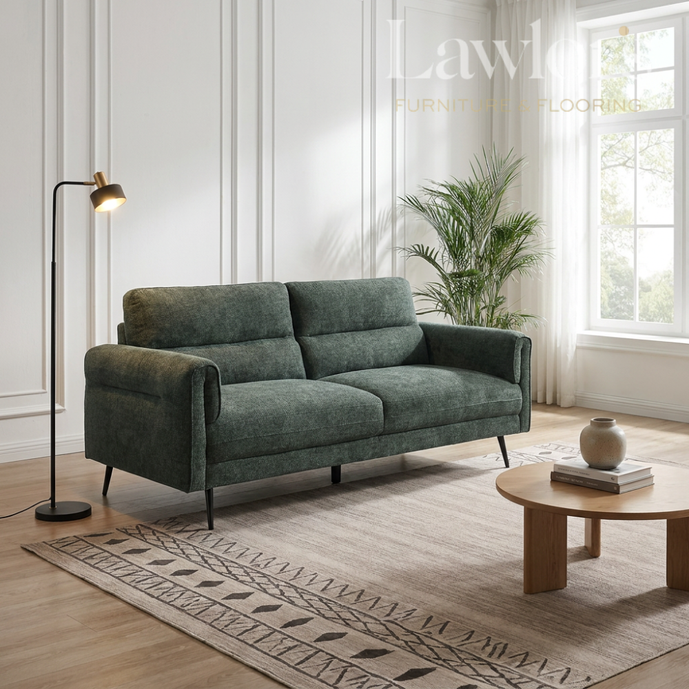 Green 3 seater sofa in a living room with a lamp, coffee table, and decorative items.