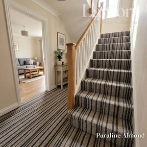Staircase with striped carpet in a home interior, featuring a mirror and furniture.
